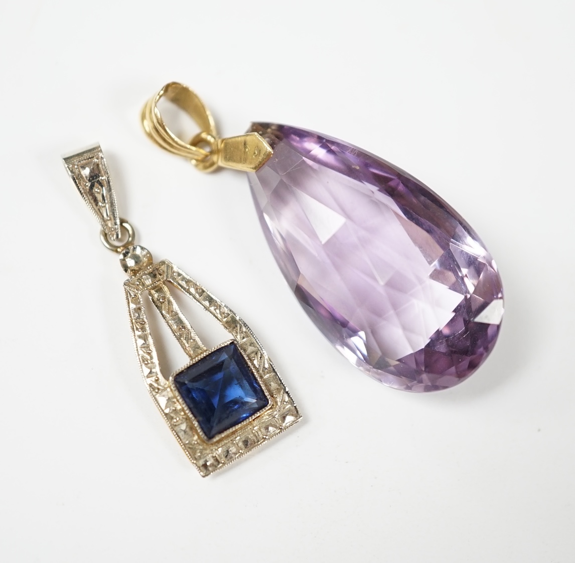 A yellow metal and fancy cut amethyst set drop pendant, 38mm, together with one other blue paste set pendant. Condition - fair